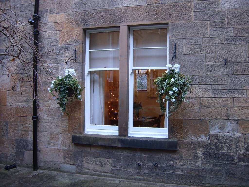 Showing our White/Cream Silk Geranium Hanging Baskets either side of a clients cottage window