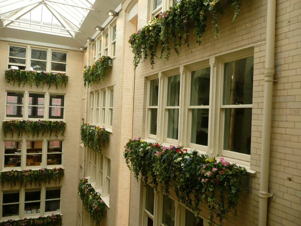 Just Artificial Limited supplied this high standard refurbished Office's Reception Atrium in Manchester with colourful Silk Trailing Flowers and Ivy, along with floor standing Artificial Plants and Trees on the Ground Floor creating a wonderful impact and great focal points of interest